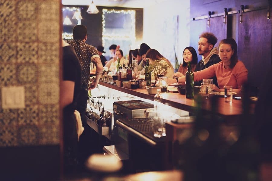 Guests seated along the candlelit bar in the evening.